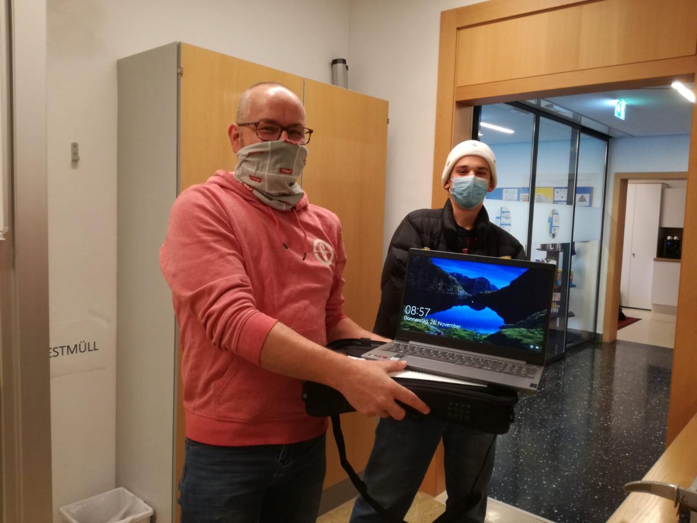 Übergabe eines Laptops an einen Schüler