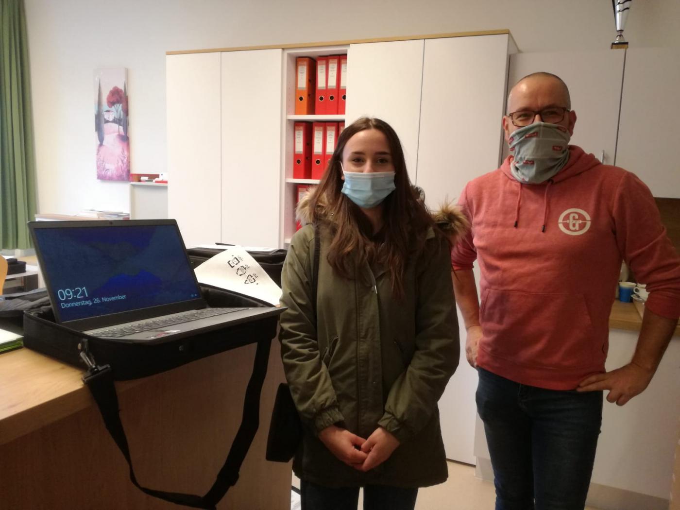 Übergabe eines Laptops an eine Schülerin